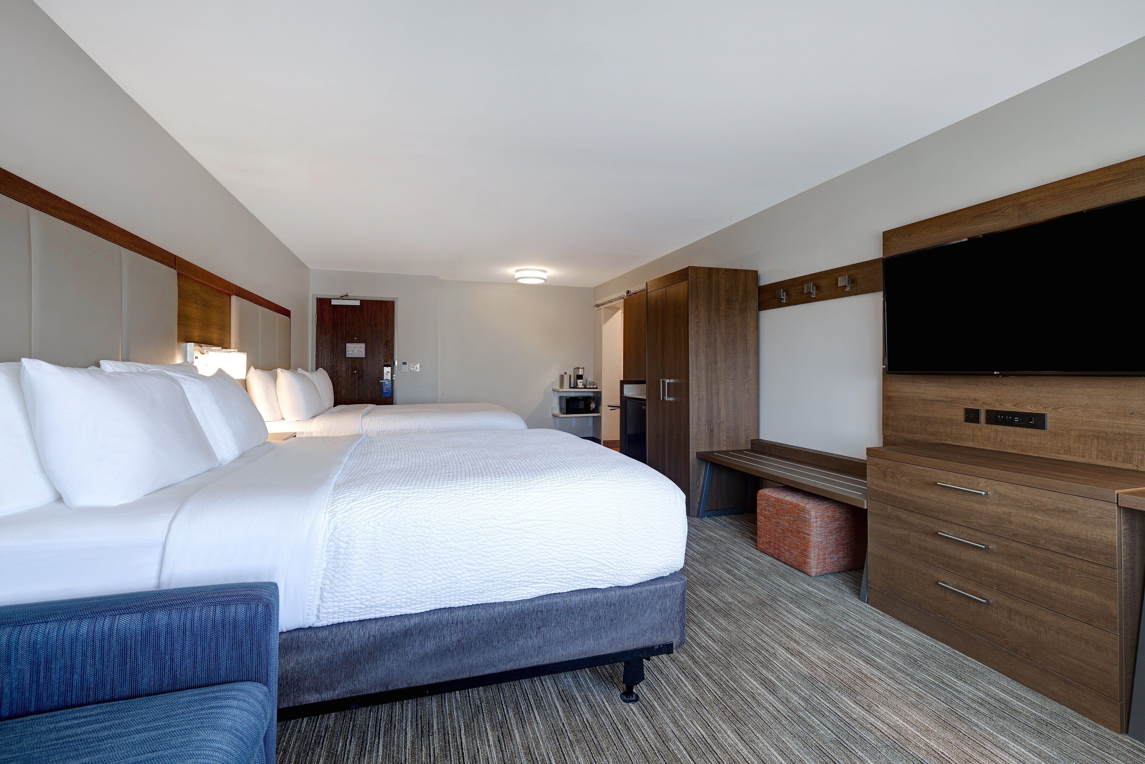 A hotel room with a large bed, a desk, a television, and a wardrobe.
