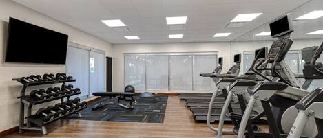 A gym with treadmills, a rowing machine, and a dumbbell rack.