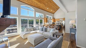 A spacious living area with a large sectional sofa, a dining table, and a kitchen in the background. - Resort-like LAKEFRONT 5br/4ba home & boathouse in quiet cove. Fun 4 all ages! (Bumpass)