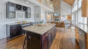 A spacious kitchen with a large island, dark wood cabinets, and a stone accent wall. - Resort-like LAKEFRONT 5br/4ba home & boathouse in quiet cove. Fun 4 all ages! (Bumpass)