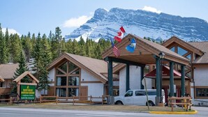 Un chalet de montagne à la structure en bois, une enseigne indiquant le « Banff Rocky Mountain Resort » et des drapeaux.