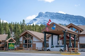 Un albergue de montaña con estructura de madera, un cartel de Banff Rocky Mountain Resort y banderas.