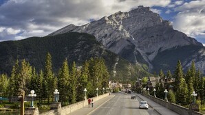 Une route menant à une montagne, avec une ville en arrière-plan.