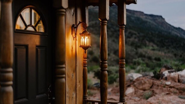 Una puerta de madera con un ventanal, un farol y vistas a un paisaje montañoso.