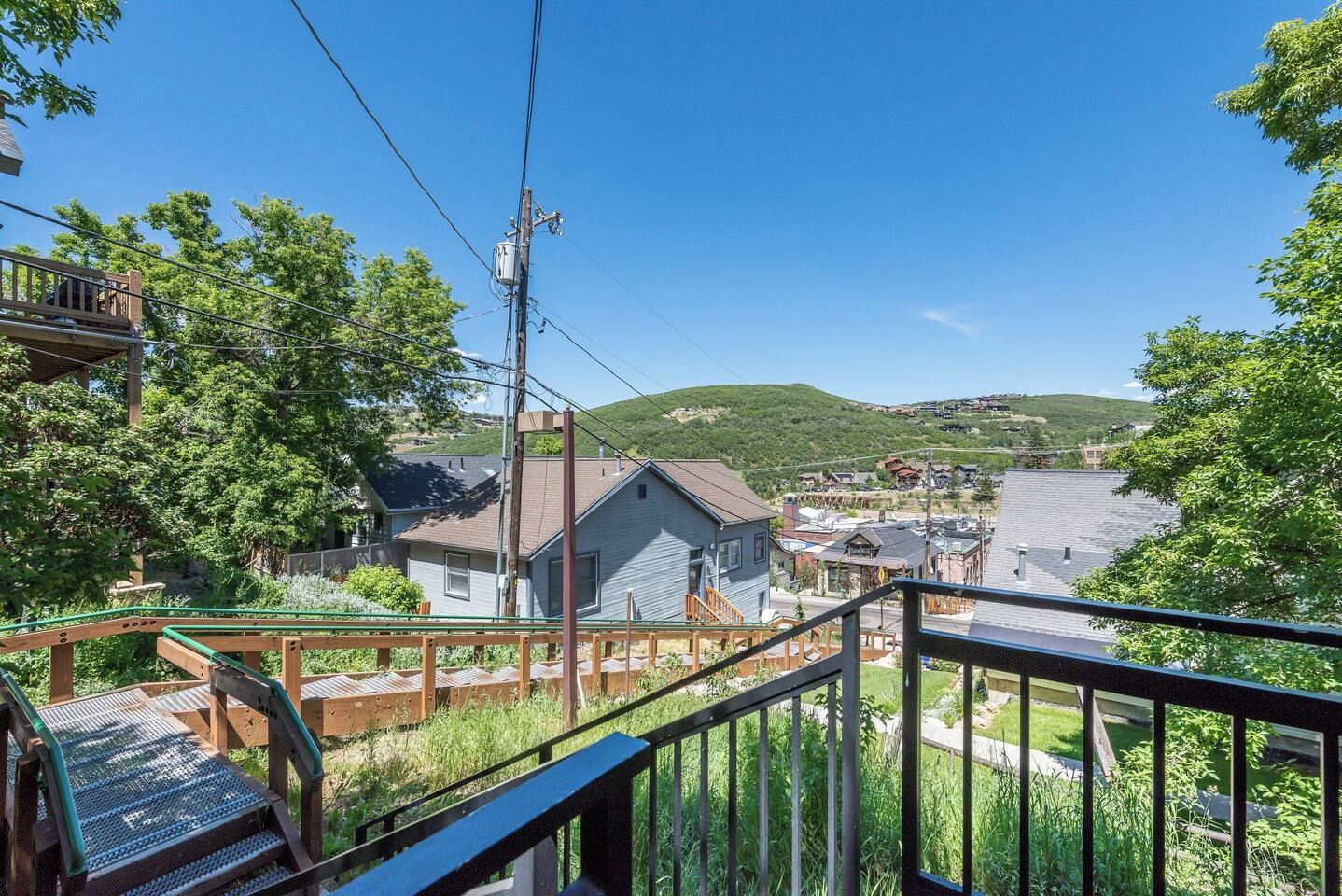 A residential area with a house, a wooden deck, and a view of a town and hills in the distance.