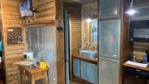 A rustic wooden interior with a wooden cabinet, a sink, and a television mounted on the wall.