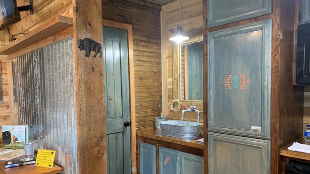 A rustic bathroom with wooden walls, a sink, and a mirror.