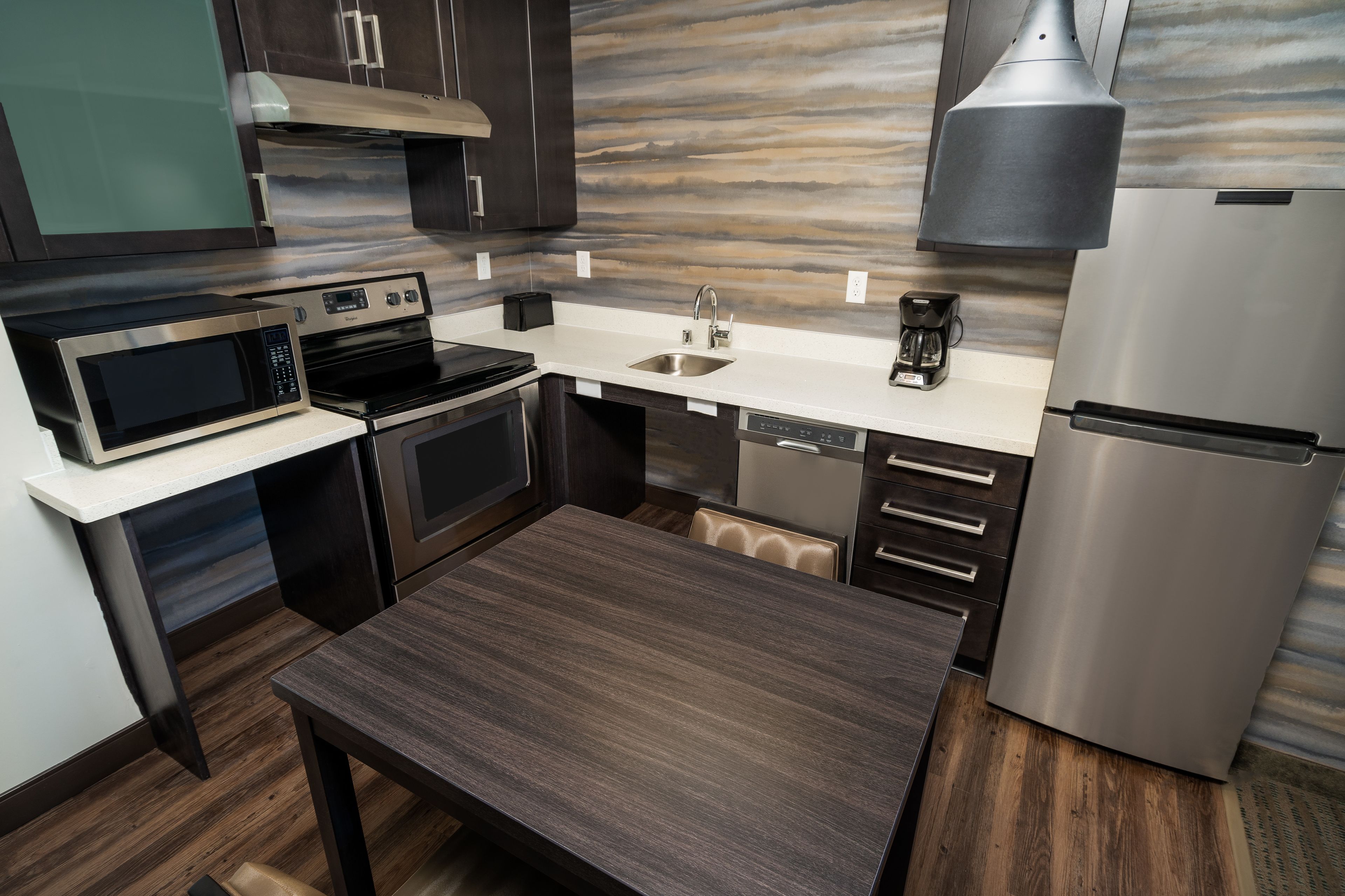 Una cocina compacta con microondas, horno, lavamanos y refrigerador.