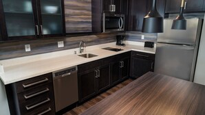 Una cocina moderna con armarios de madera oscura, electrodomésticos de acero inoxidable y encimera de color claro.