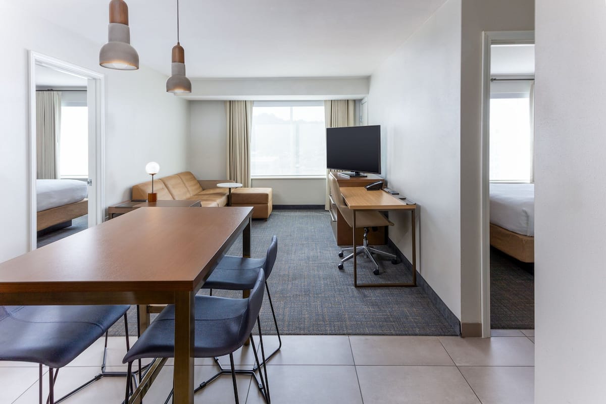 Une chambre d’hôtel comprenant un lit, un bureau avec un ordinateur, une télévision, un canapé et une table à manger avec des chaises.