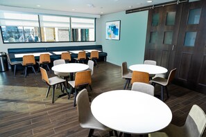 Enjoy meals in a stylish dining area with round and square tables, comfortable chairs, and large windows.