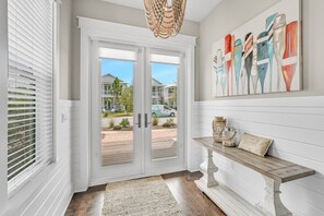 A hallway with a white door, a bench, and a colorful abstract painting on the wall. - Golf Cart! Walk to the Pool & Beach! 3 Kings! 8 Bikes! Tons of Fun! Stay Awhile at NatureWalk on 30A (Santa Rosa Beach)