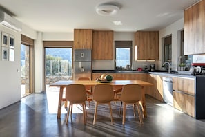 A modern kitchen with wooden cabinets, a stainless steel refrigerator, and a dining area with four chairs.
