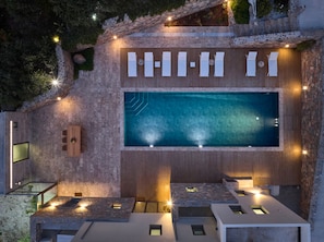 A rooftop pool area with a wooden deck, seating, and a large pool.