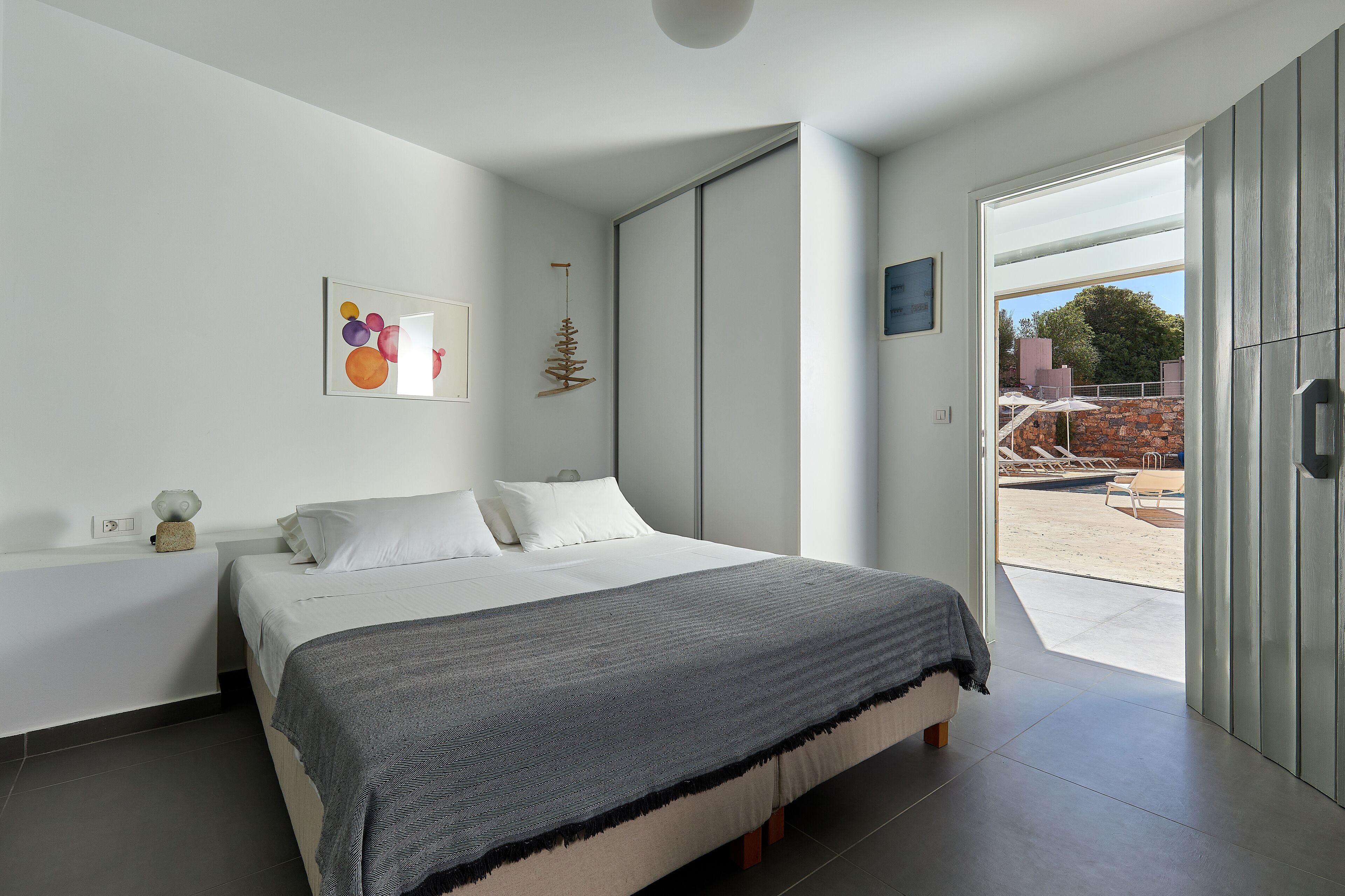 A modern bedroom with a large bed, a view to the outside, and a minimalist decor.