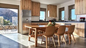 Een moderne keuken met houten kastjes, een roestvrijstalen koelkast, en een eethoek met een houten tafel en stoelen.