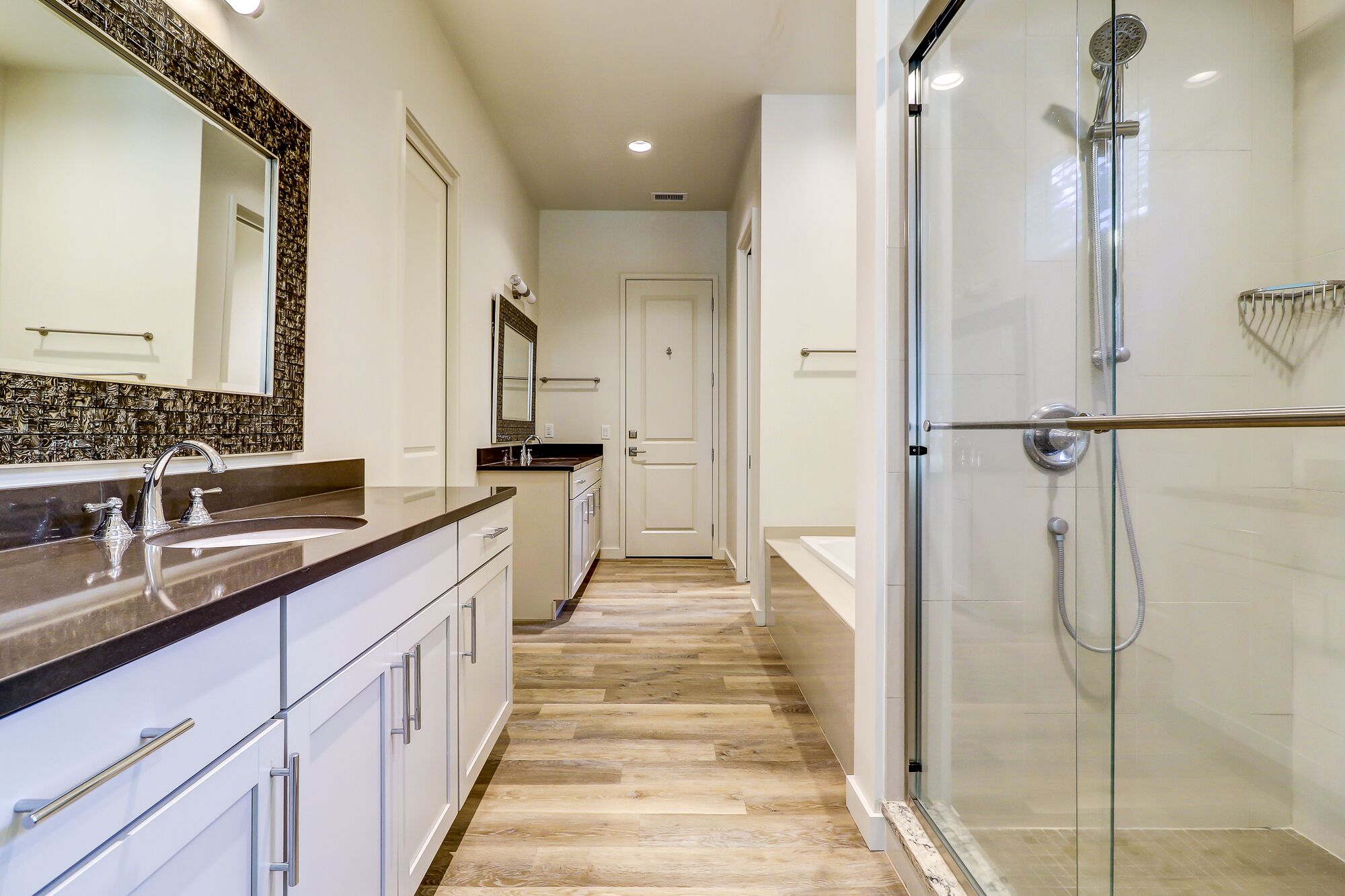 A modern bathroom with a glass shower enclosure, a double sink vanity, and a walk-in shower.