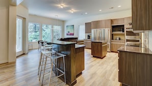 Eine moderne Küche mit Holzsäcken, Edelstahlgeräten und einer Bar mit Hockern.