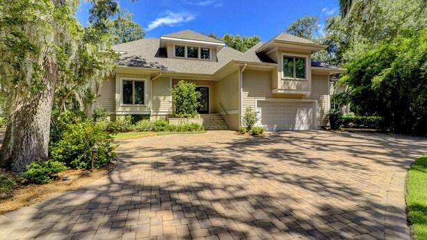 A two-story house with a brick driveway, a front porch, and a garage.