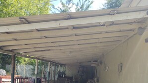 Un espace extérieur abrité, doté d’un sol en béton, d’un mur avec des prises électriques et d’un coffret de raccordement.