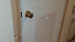 Une porte blanche avec une poignée de porte en laiton et une petite fenêtre.