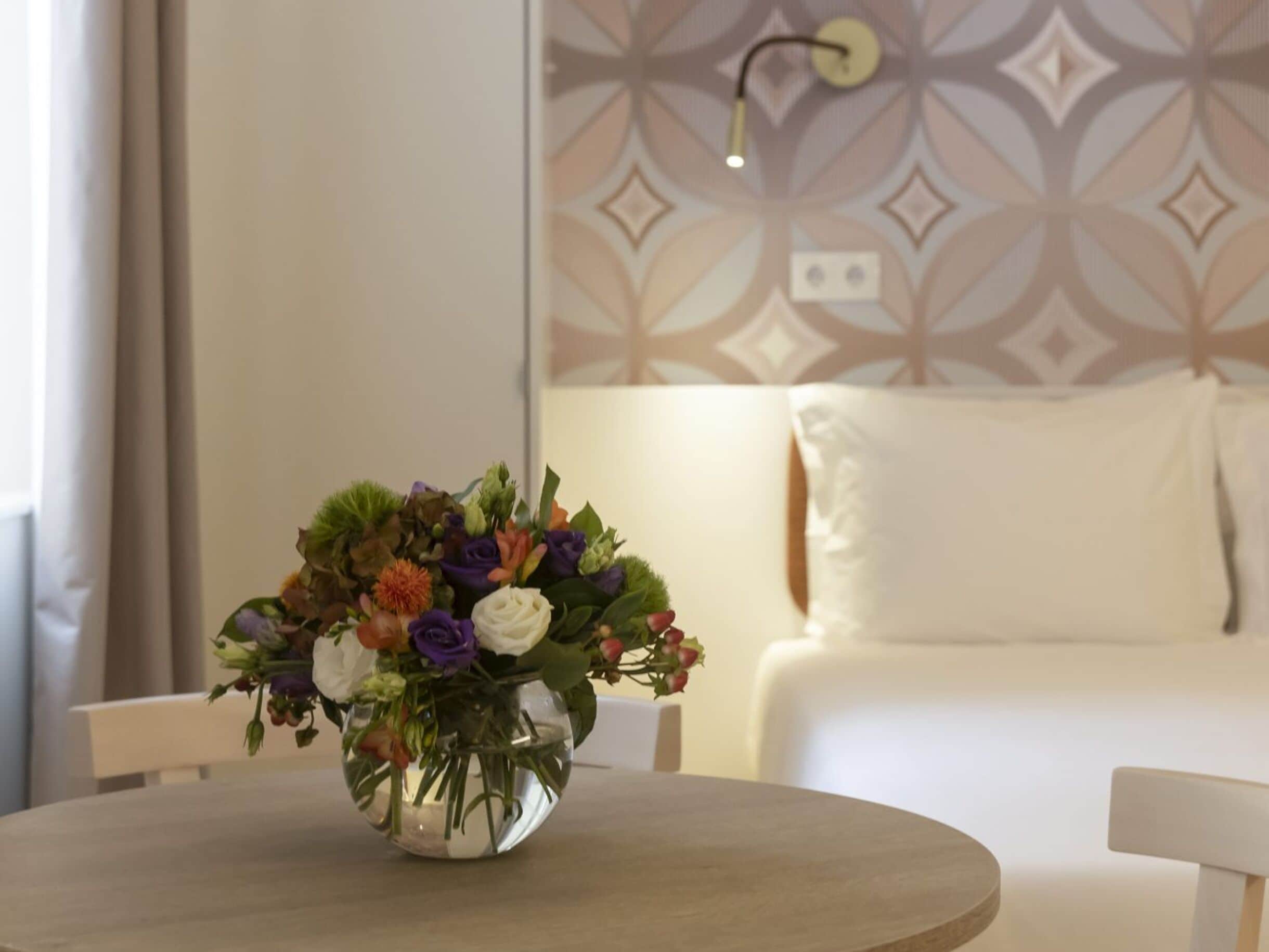 A round table with a clear glass vase containing a bouquet of flowers.