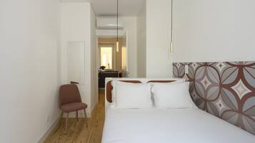 Una habitación de hotel con cama, una silla, un escritorio y un equipo de aire acondicionado.