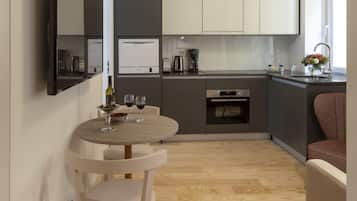 Uma cozinha moderna com área de refeições, incluindo uma mesa com cadeiras, uma cafeteira e uma taça de vinho.