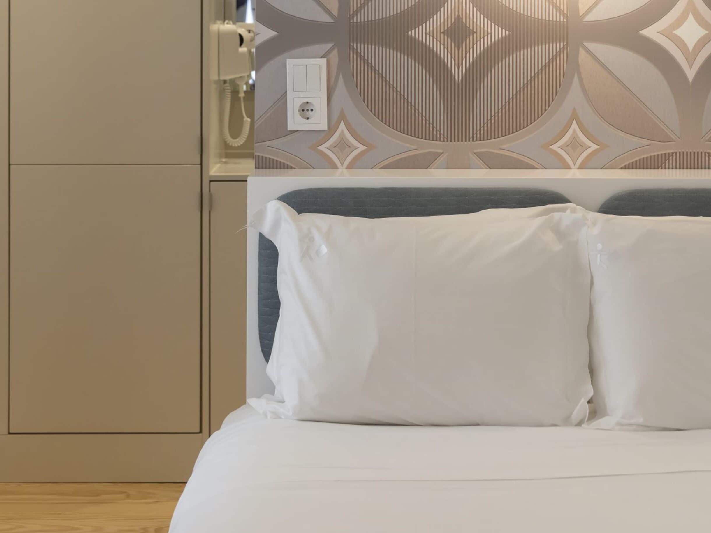 Une chambre d’hôtel équipée d’un lit, d’un téléphone fixé au mur et d’une prise de courant.