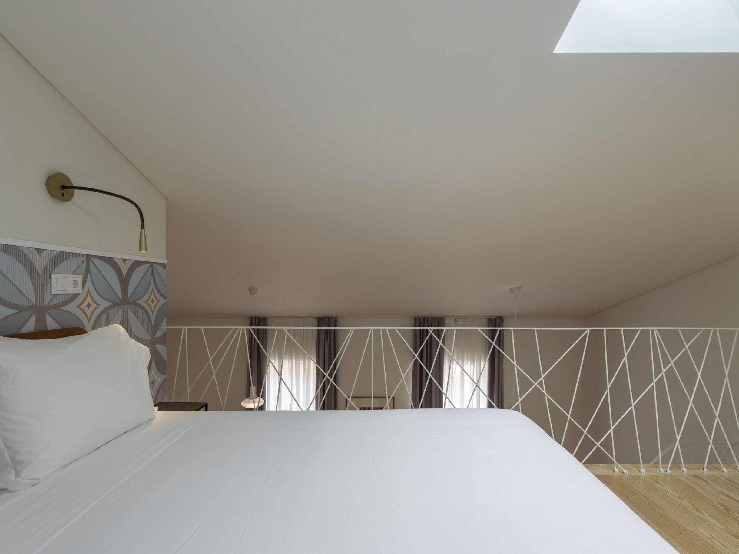 Une chambre à coucher avec un lit, une lucarne, un mur à motifs et un plafond blanc.