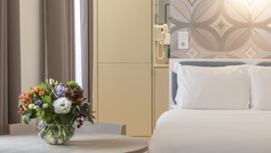Een hotelkamer met een bed, een ronde tafel met een bloevas en een muur met een geometrisch patroon.