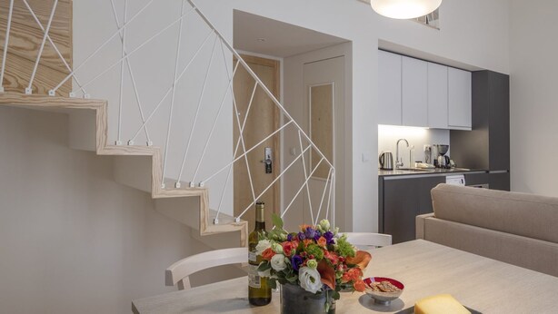 Een moderne keuken met een inbouwoven, een eethoek met een tafel gedekt voor een maaltijd, en een trap met een geometrisch ontwerp.