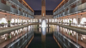 A courtyard with a central fountain, a tower, and outdoor seating areas. - Van der Valk Hotel Mechelen (Mechelen)