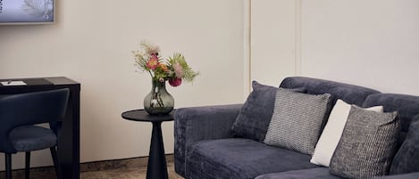 Una sala de estar moderna con un sofá gris, una mesita redonda con un florero y una silla negra.