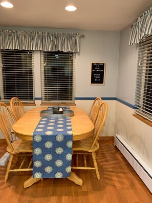 A dining area with a round table, wooden chairs, a blue tablecloth, and a sign welcoming guests to the lakehouse. - Private waterfront lake home, Fox Tail Bay, Silver Lake, Wautoma, WI (Wautoma)