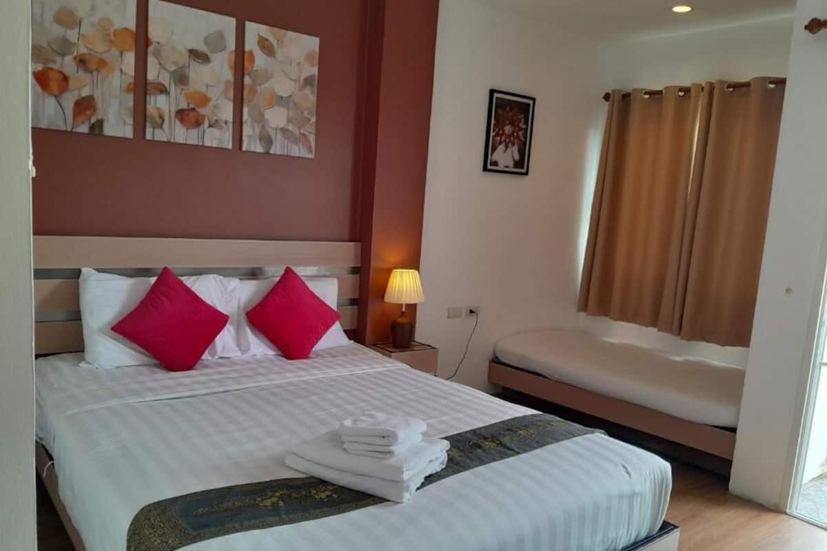A hotel room with a bed, a bedside table with a lamp, a wall-mounted artwork, and a window with curtains.