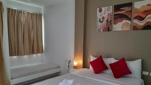 A hotel room with a bed, a bench, and artwork on the wall. - Island Patong Beachfront Apartments (Patong)