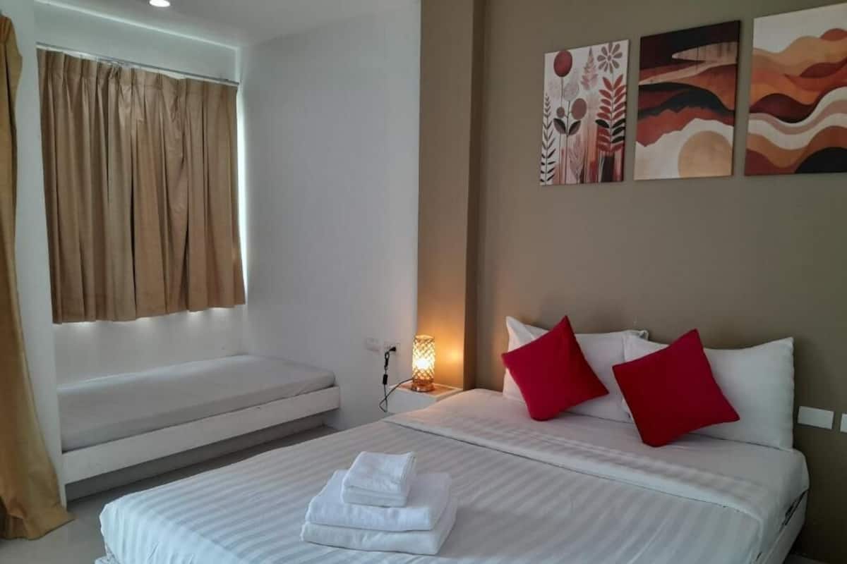 A hotel room with a bed, a bench, and artwork on the wall.