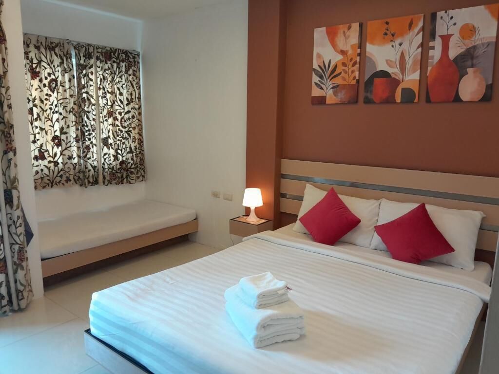 A hotel room with a bed, a nightstand with a lamp, a bench, and artwork on the wall.