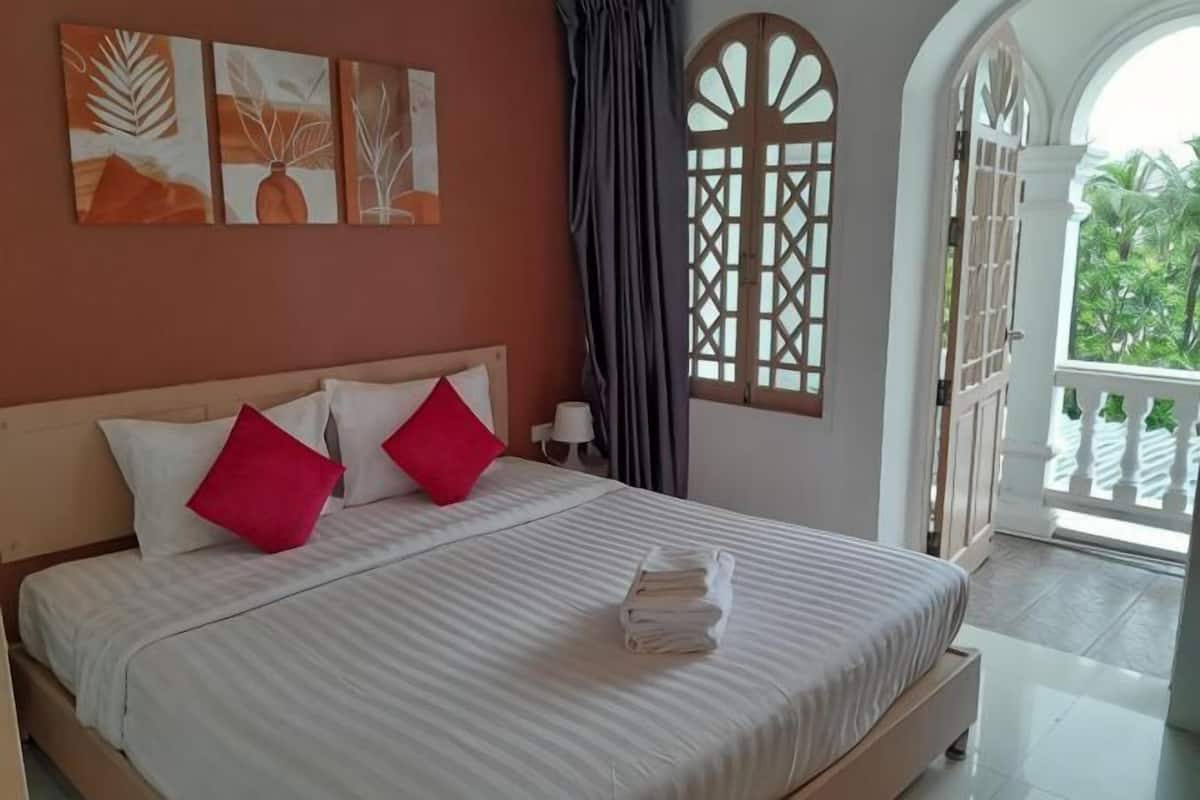 A bedroom with a bed, pillows, a nightstand, and a window with a view.
