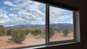Ein Fenster mit Blick auf eine Wüstenlandschaft, einschließlich Bäume und ferner Berge.