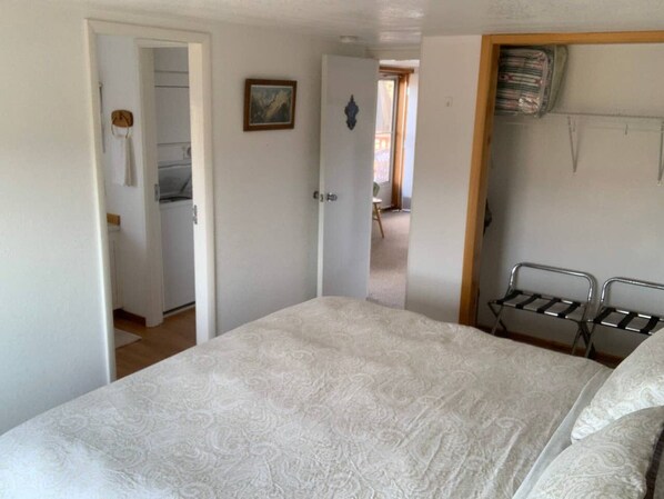 Une chambre à coucher comprenant un lit, une armoire et une porte donnant sur une autre pièce.