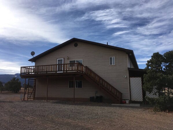 A two-story house with a balcony, a staircase, and a fenced yard.