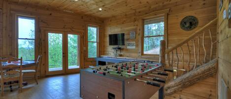 A wooden-floored room with a foosball table, a television, and a staircase.