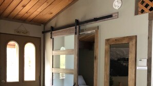A room with a wooden ceiling, a sliding glass door leading to a bed, and a small window with a view. - Cozy and quaint pet friendly cabin (Georgetown)