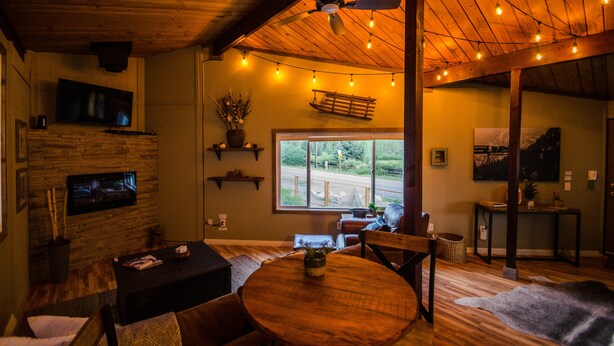 A cozy living room with a fireplace, wooden ceiling, and string lights. - Cozy and quaint pet friendly cabin (Georgetown)