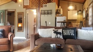 A cozy living room with a brown leather sofa, a coffee table, and a fireplace. - Cozy and quaint pet friendly cabin (Georgetown)