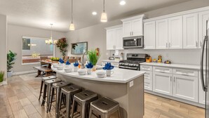 A modern kitchen with white cabinets, stainless steel appliances, and a central island with bar stools.