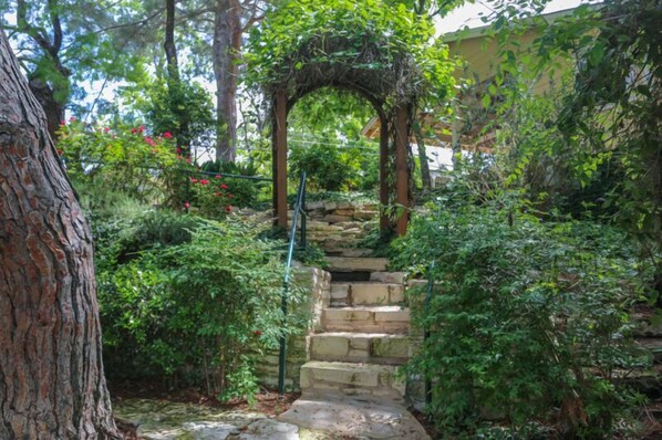 A stone staircase leading up to a wooden archway surrounded by lush greenery.
