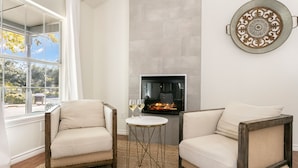 A living room with two armchairs, a small round table, and a fireplace.